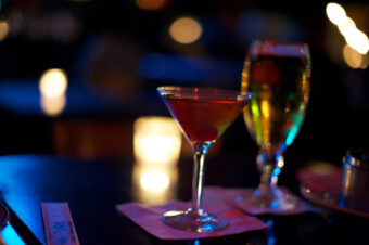 red drink in a chilled cocktail glass, on a bar in a dark room