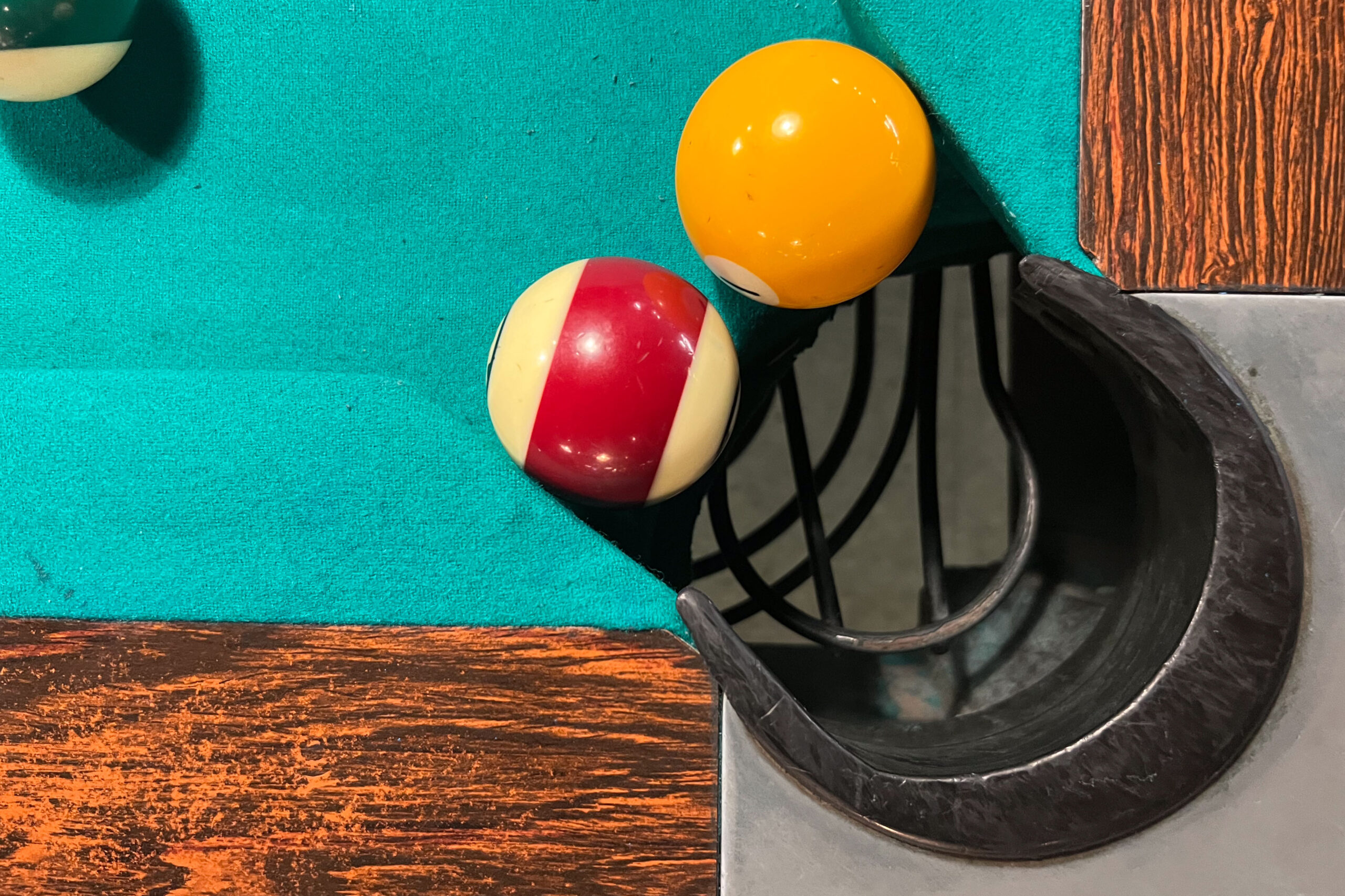Billiard table with two balls inside the jaws of a corner pocket, showing there is ample room for both, with plenty of additional space between them.