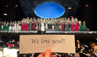 Opera cast at the end of Lohengrin, a hand holding a paper saying "We Love You"